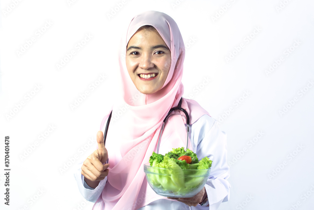 Portrait of Muslim female doctor with vegetable standing on white background Portrait of Muslim female doctor with vegetable standing on white background