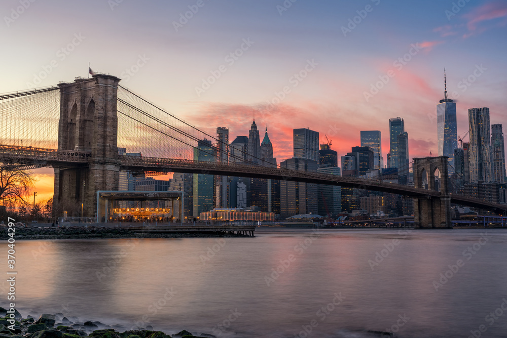 Colorful Pink Sunset Behind The Brooklyn Bridge and New York Skyline