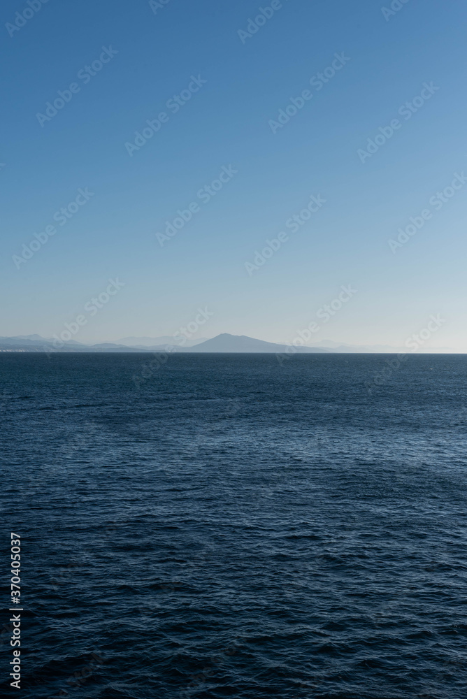 paisaje de mar con cielo azul y montes en el horizonte