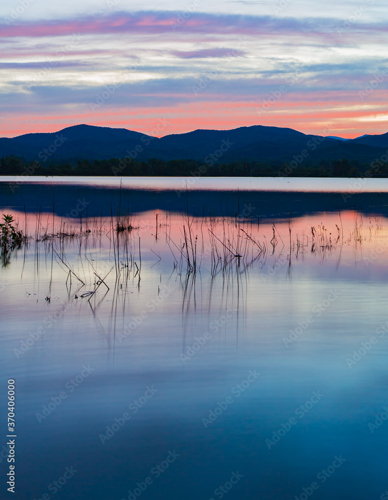 Blue ridge mounains reflect sunset's colors over calm water