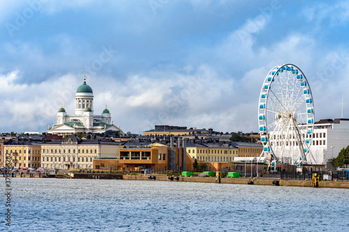 View of Helsinki Harbor on a cloudy day. Ferris wheel in Helsinki. Sights of the capital of Finland. Church Of St. Nicholas. Low houses on the waterfront. Travel to Scandinavia.