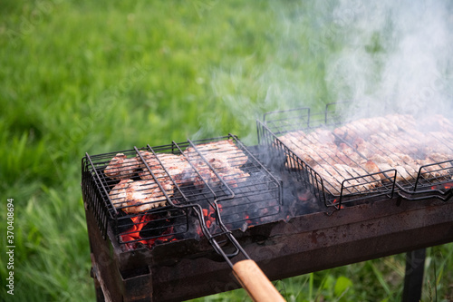 Cooking barbeque meat on grill outdoor on a lawn