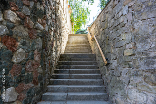 A stone staircase with a railing leading up.Summer day. © Sofya