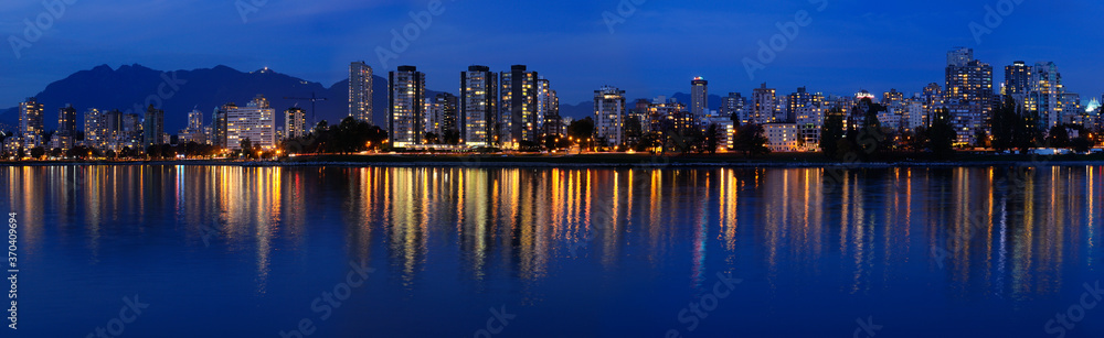 Panorama of West End Vancouver skyline at twilight reflected in English Bay from Vanier Park