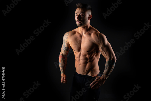 Handsome muscular male bodybuilder on a black background. Strong man.