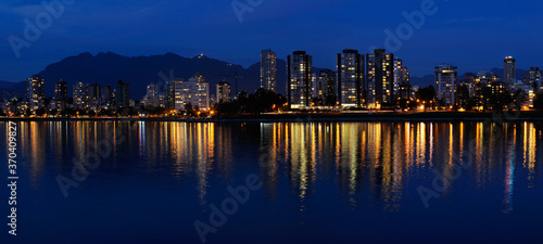 Panorama of West End Vancouver skyline at dusk reflected in English Bay with Grouse Mountain