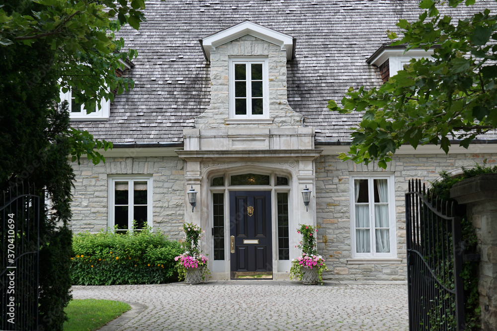 Elegant gated entrance to stone house  with dormer window and cedar shingle roof
