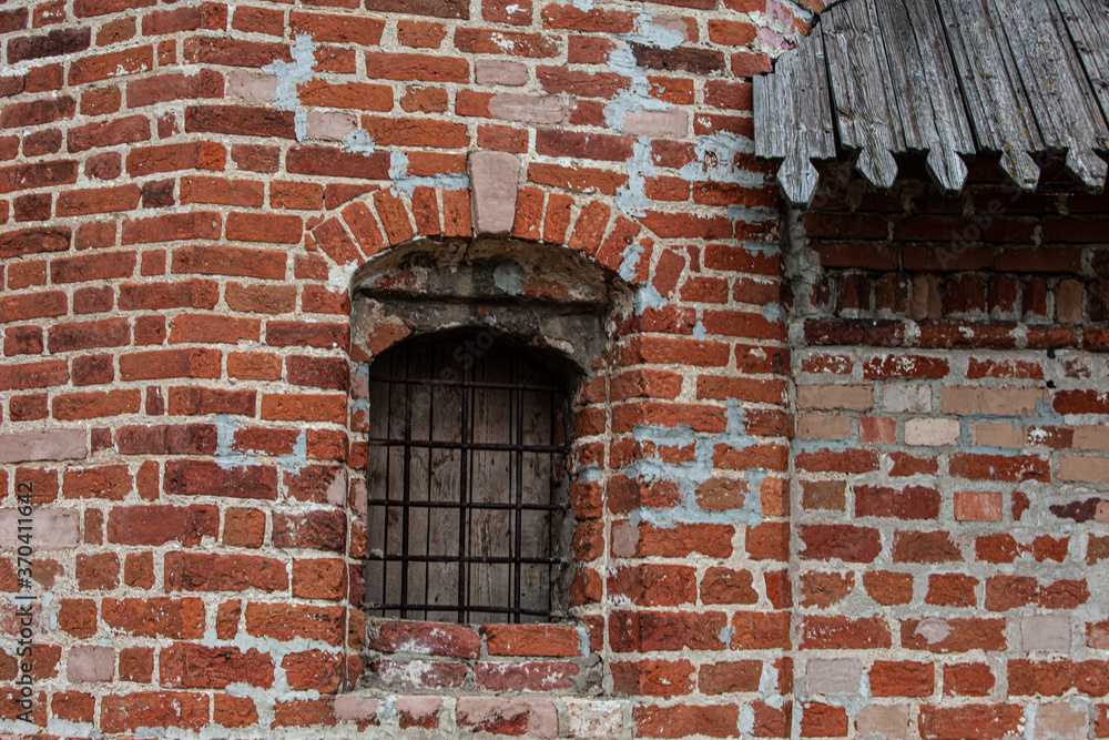Fragment of old brick kremlin wall with window and timber roof