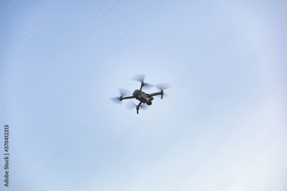 Drone flying in the air with blue sky in the background. Outdoor photo Drone flying in the air with blue sky in the background. Outdoor photo