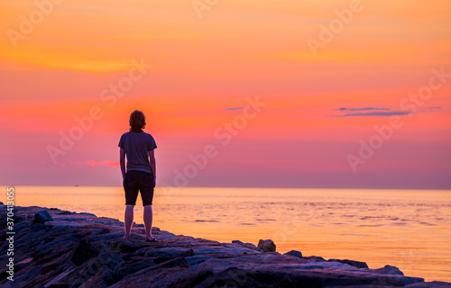 Young man admires the rising sun in June photo