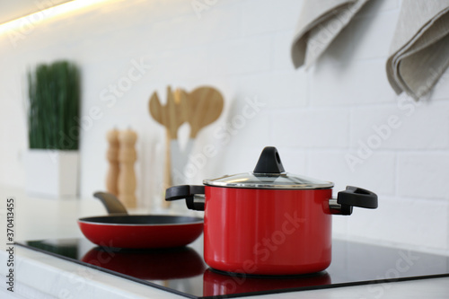 Red pot and frying pan on stove in kitchen