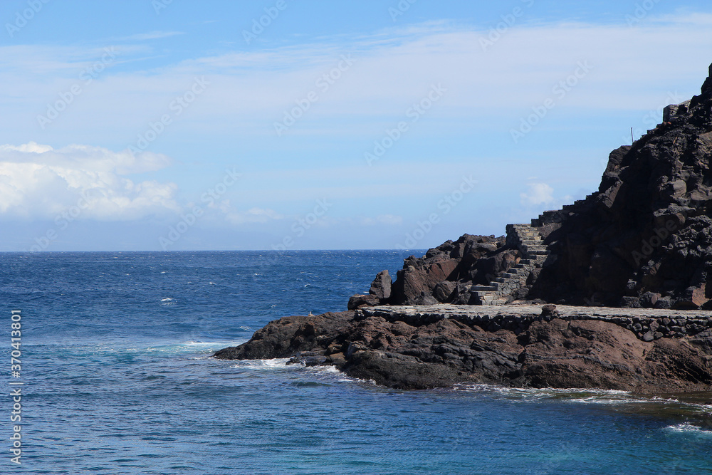Black rocks surrounded by the sea with a stone staircase. Seascape. Black rocks surrounded by the sea with a stone staircase. Seascape.