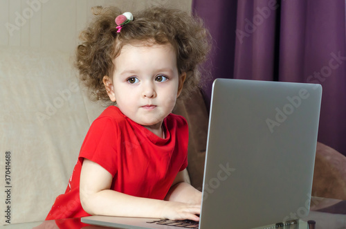 home, leisure, games, online learning, technology and internet concept - little serious girl with laptop at home. Mockup, place for text.