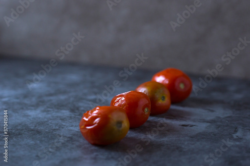 Four pickled tomatoes on a gray background