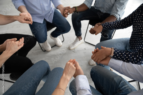 Close up diverse people sitting on chairs in circle at group training counselling session  holding hands  psychological help and treatment concept  drug or alcohol addiction rehabilitation