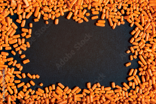 Orange sprinkles frame on black background, halloween theme photo