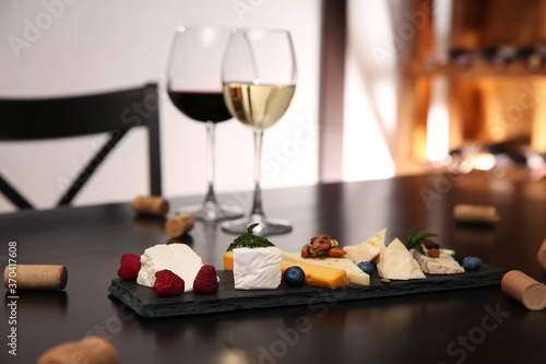 Different types of delicious cheeses with berries and nuts on table