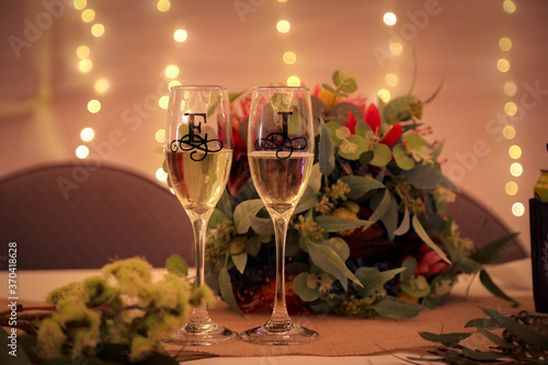 Champagne flutes on bridal table at wedding reception decorated with letters E and J with bokeh background