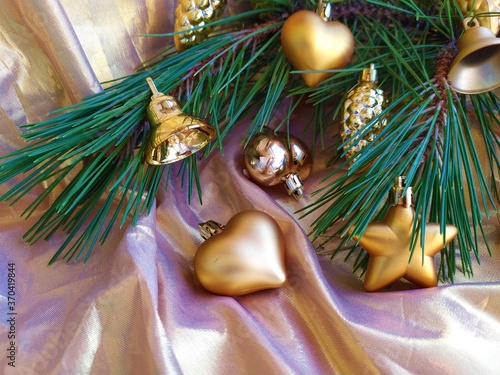 Fresh green pine branch with colden christmas toys on a golden background photo