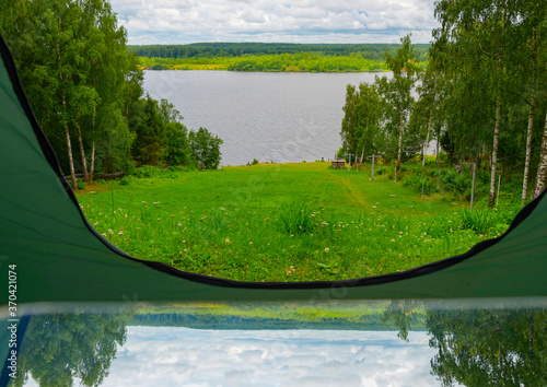 reflection and view from camping tent on the river bank in a picturesque landscape