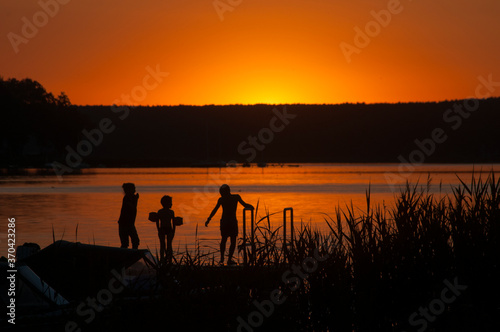 Dzieci kąpią się w jeziorze podczas widowiskowego zachodu słońca