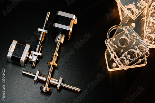 motor and guides for the laser machine. details of the engraving machine, black warm background, orange light. photo