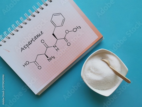 Structural chemical formula of aspartame molecule with artificial sweetener in white bowl. Aspartame is an artificial sweetener used as a sugar substitute in low-calorie food and drinks. photo