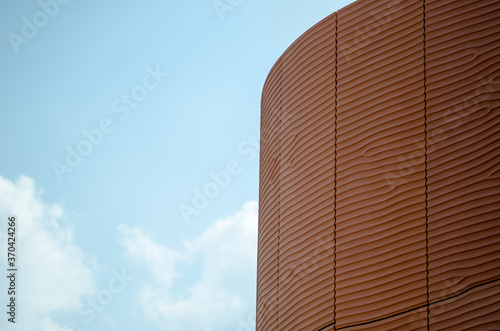 Background perspectives, which reflect the facade of a building with prefabricated panels of red concrete that recalls the silhouettes such as sand dunes in the desert smoothed by the wind, of the sea