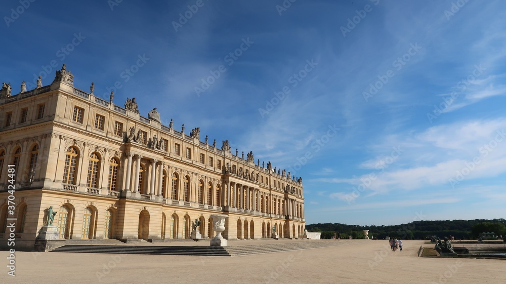 Obraz premium Château de Versailles côté jardin, vue sur la façade du corps central du palais royal et sa terrasse, sous un ciel bleu (France)