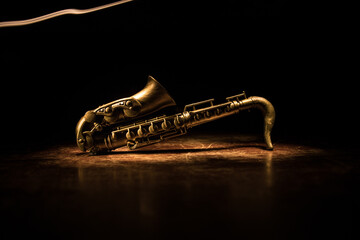 Alto gold sax miniature with colorful toned light on foggy background. Saxophone music instrument in lowlight. Selective focus