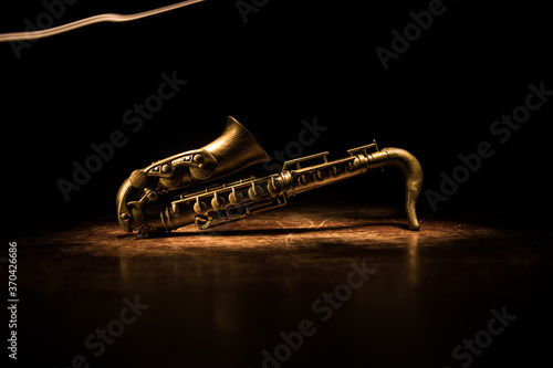 Alto gold sax miniature with colorful toned light on foggy background. Saxophone music instrument in lowlight. Selective focus