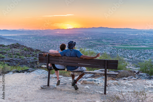 An interracial couple watches the sun go down from South Mountain in Phoenix, Arizona.