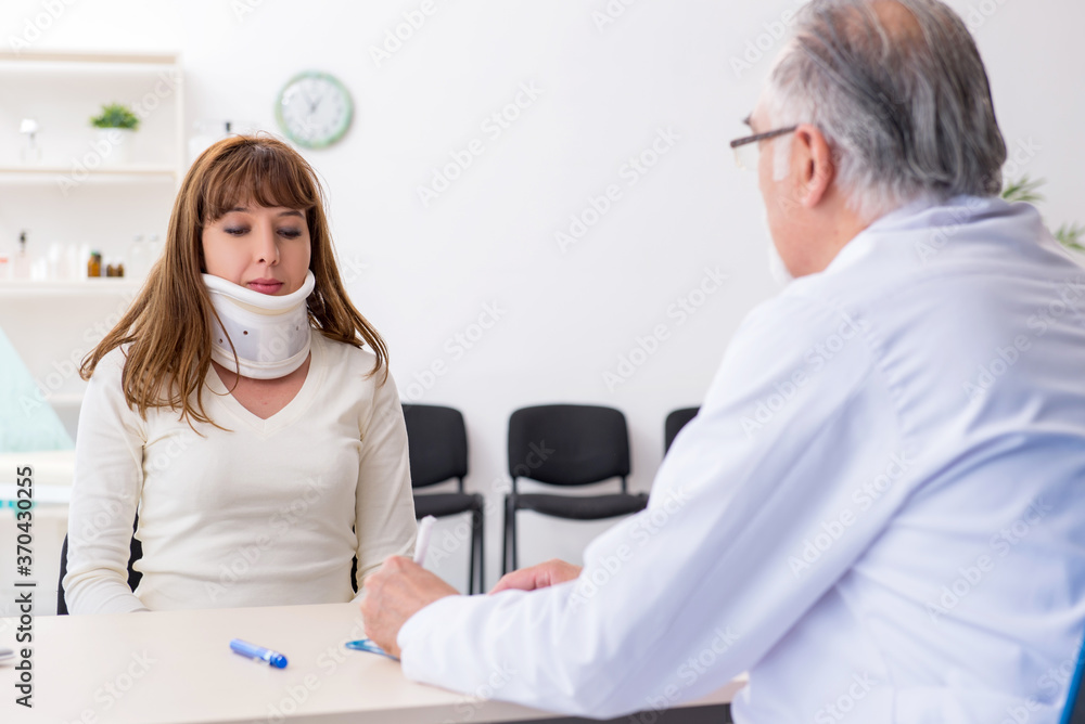 Fototapeta premium Young injured woman visiting experienced doctor traumatologist
