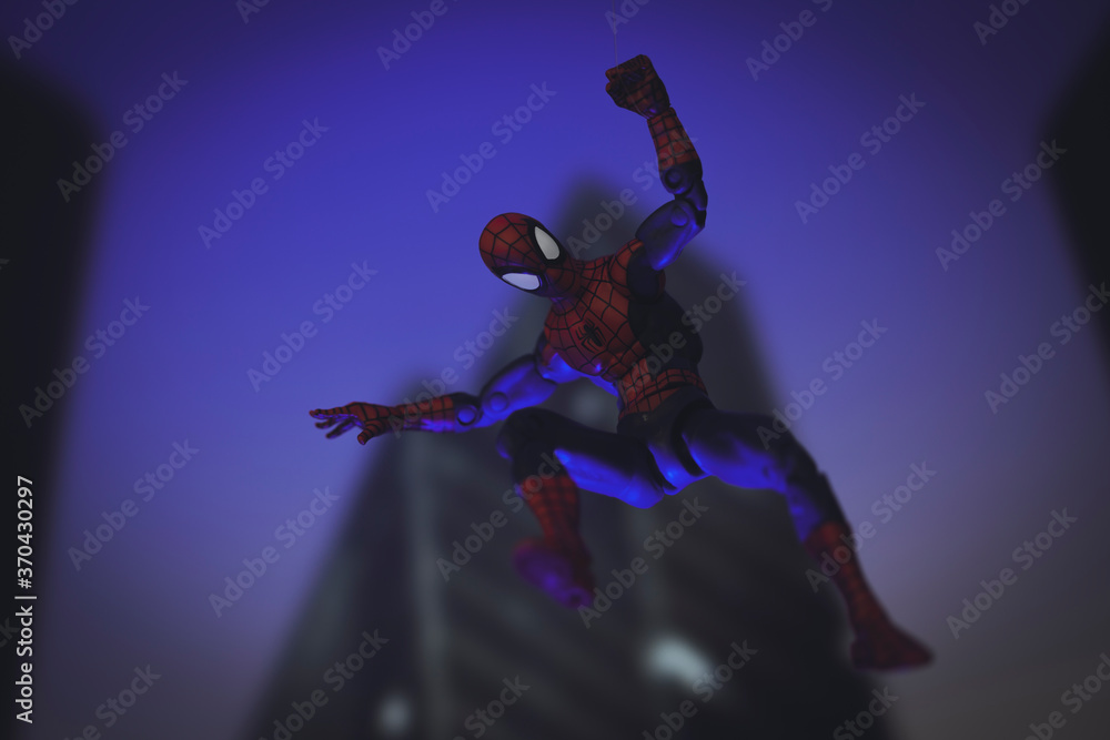 Naklejka premium NEW YORK USA - AUGUST 9 2020: Marvel comics superhero Spiderman swinging from a web at night - Hasbro action figure