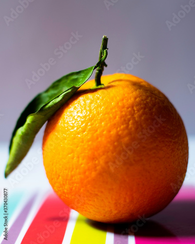 Fresh orange with leaf  on colorful tray photo