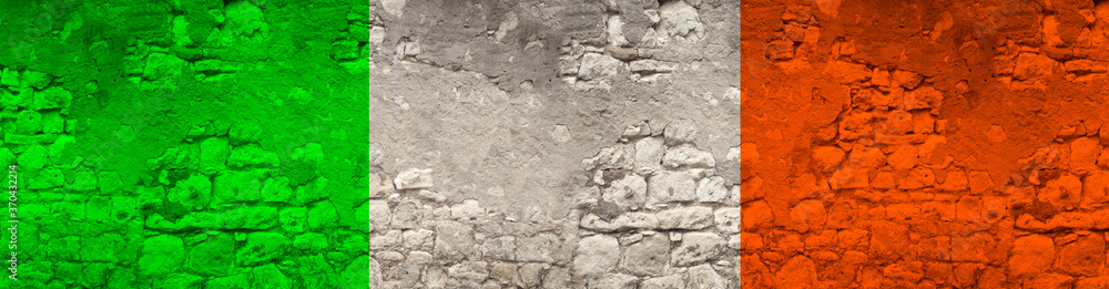 seamless panorama of the national flag of the state of Ireland on an old stone wall with cracks, the concept of tourism, emigration, economy, politics, global world trade
