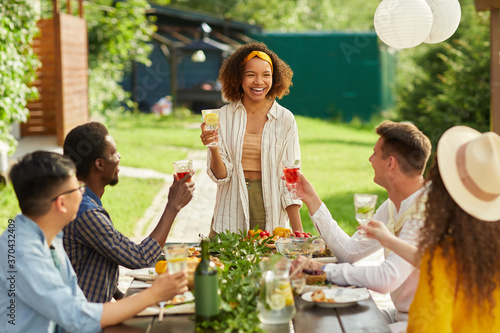 Portrait of young African-American woman laughing cheerfully while enjoying dinner with friends at outdoor terrace in Summer, copy space photo