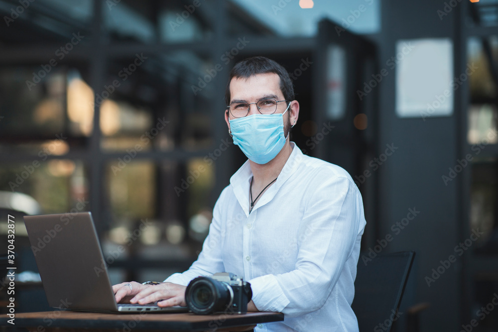 An authentic looking turkish young man works with a laptop in a modern cafe with new normal concept An authentic looking turkish young man works with a laptop in a modern cafe with new normal concept
