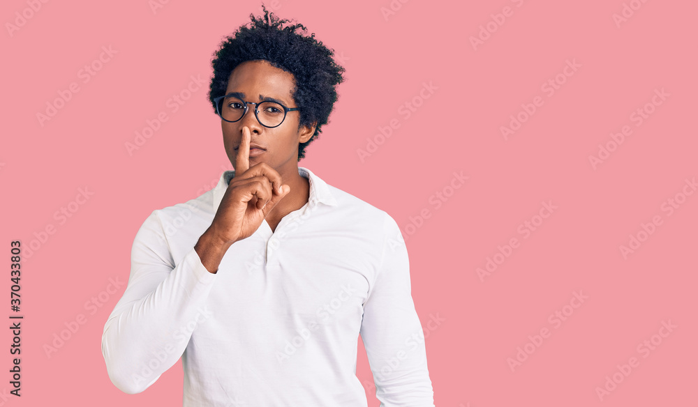 Handsome african american man with afro hair wearing casual clothes and glasses asking to be quiet with finger on lips. silence and secret concept. Handsome african american man with afro hair wearing casual clothes and glasses asking to be quiet with finger on lips. silence and secret concept.