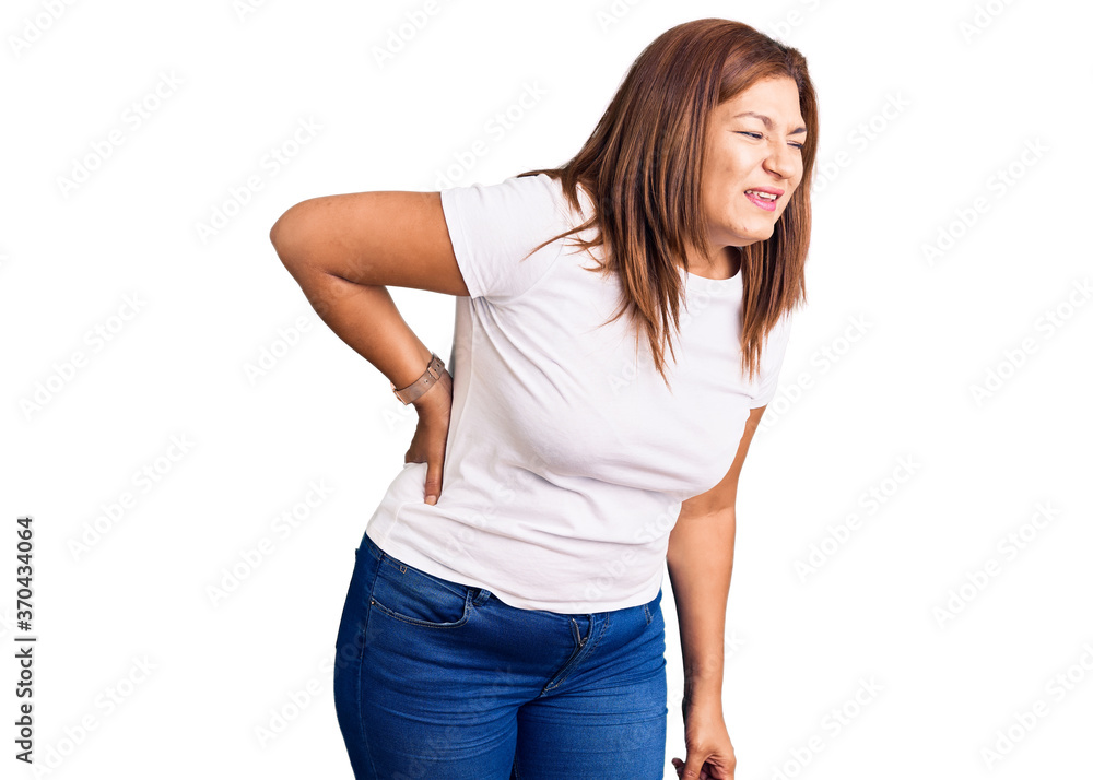 Middle age latin woman wearing casual white tshirt suffering of backache, touching back with hand, muscular pain Middle age latin woman wearing casual white tshirt suffering of backache, touching back with hand, muscular pain