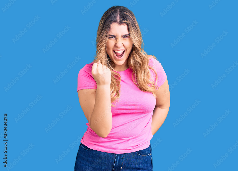 Young caucasian woman wearing sportswear angry and mad raising fist frustrated and furious while shouting with anger. rage and aggressive concept. Young caucasian woman wearing sportswear angry and mad raising fist frustrated and furious while shouting with anger. rage and aggressive concept.