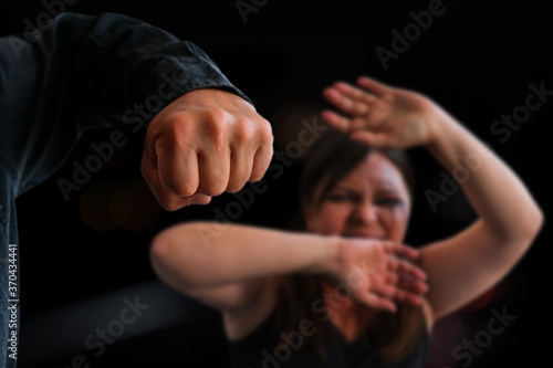 big male fist of aggressive man threatens crying woman, hits her, concept of psychological gaslighting, beating, aggression, domestic violence