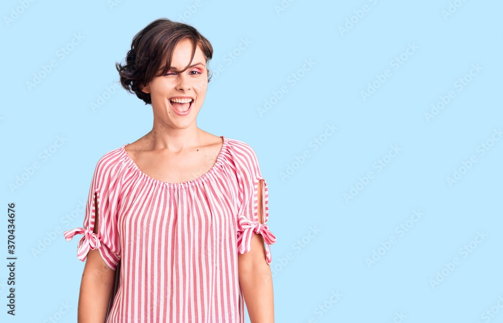 Beautiful young woman with short hair wearing casual summer clothes winking looking at the camera with sexy expression, cheerful and happy face. Beautiful young woman with short hair wearing casual summer clothes winking looking at the camera with sexy expression, cheerful and happy face.