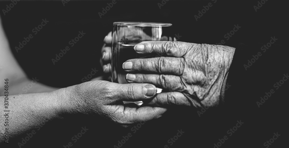 Fototapeta premium Water in hands, helping the elderly, black and white photo