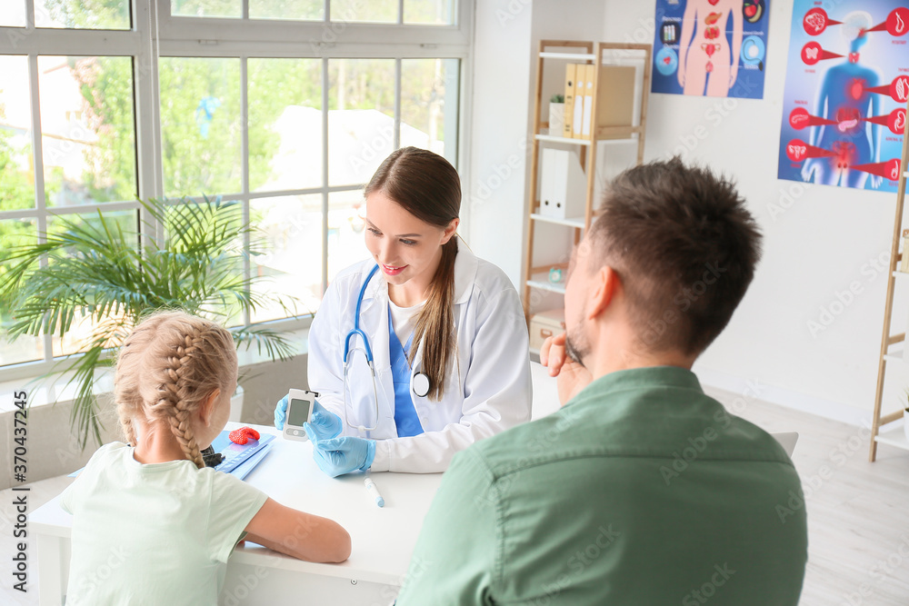 Doctor measuring blood sugar level of little girl in clinic Doctor measuring blood sugar level of little girl in clinic