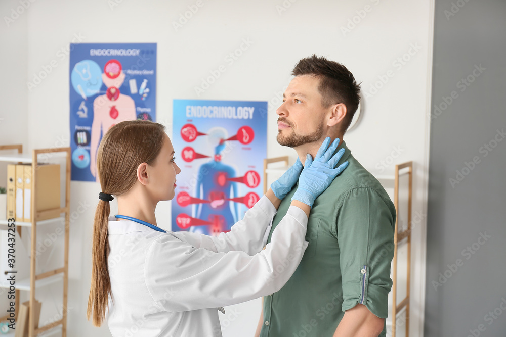 Fototapeta premium Doctor examining man with thyroid gland problem in clinic