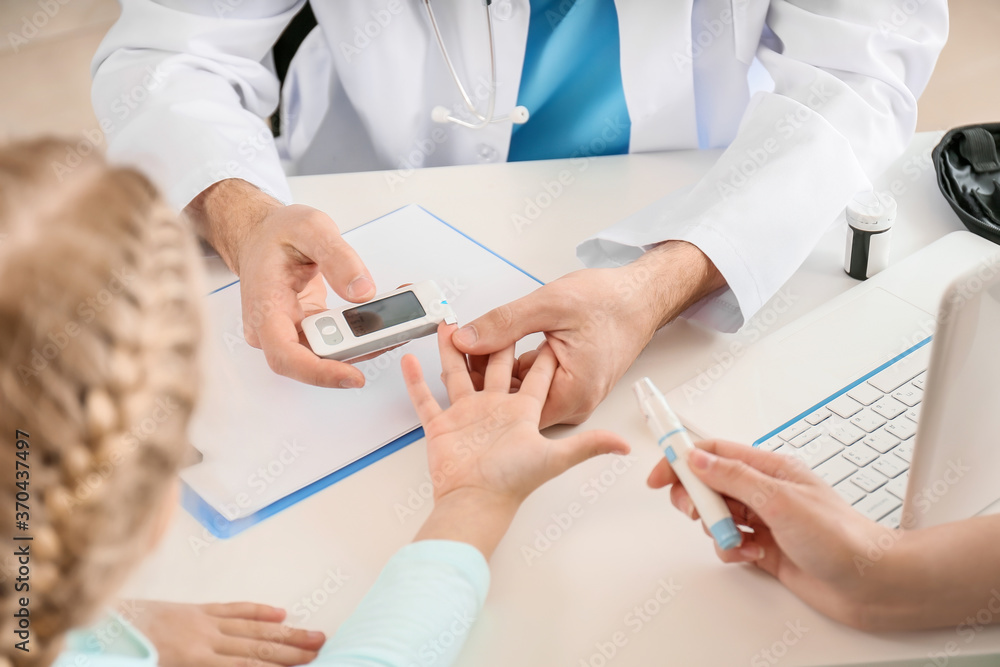 Doctor measuring blood sugar level of little girl in clinic Doctor measuring blood sugar level of little girl in clinic
