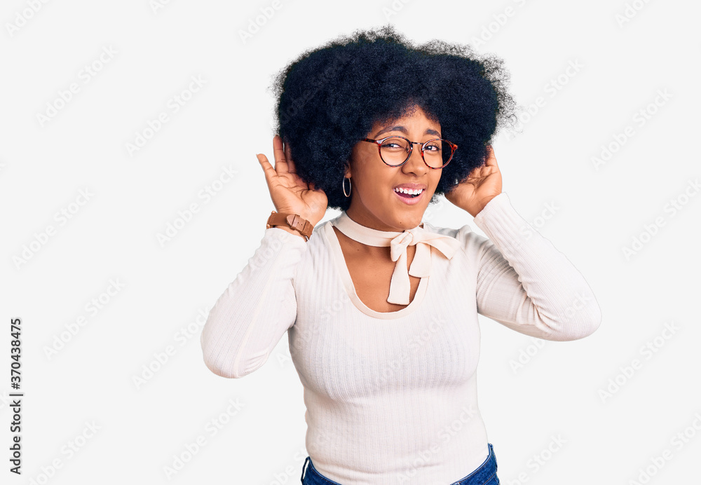 Young african american girl wearing casual clothes and glasses trying to hear both hands on ear gesture, curious for gossip. hearing problem, deaf Young african american girl wearing casual clothes and glasses trying to hear both hands on ear gesture, curious for gossip. hearing problem, deaf
