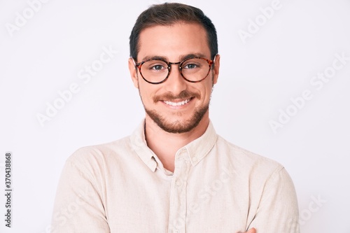 Young handsome man wearing casual clothes and glasses happy face smiling with crossed arms looking at the camera. positive person. © Krakenimages.com