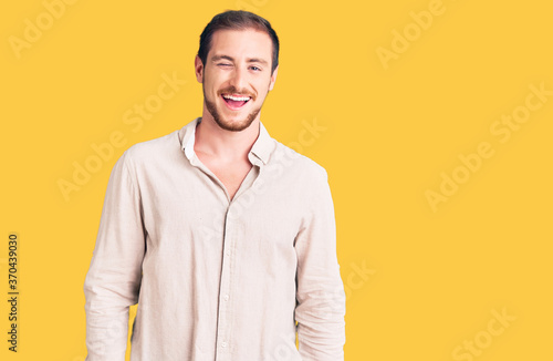 Young handsome caucasian man wearing casual clothes winking looking at the camera with sexy expression, cheerful and happy face.